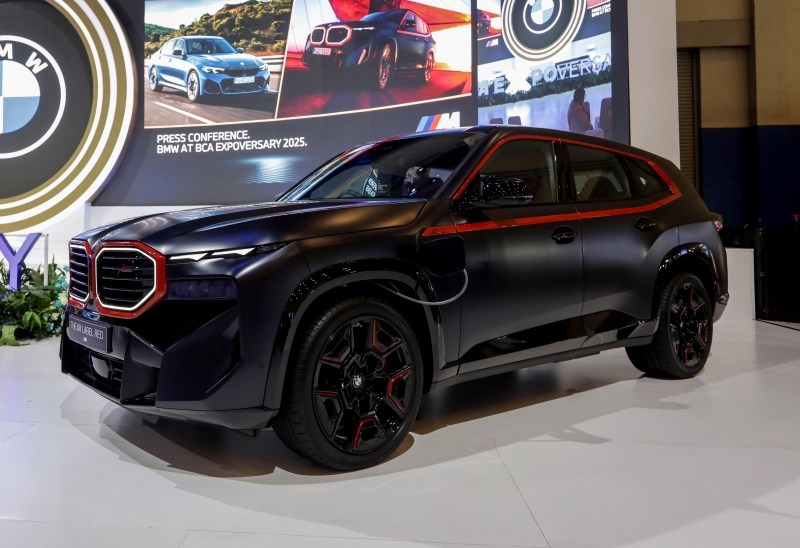 October 30, 2026 GAET OTOMOTIF - Peristiwa Terbaru Dunia Otomotif Black SUV on display at an auto show with red accents and large screens in the background showing BMW imagery.