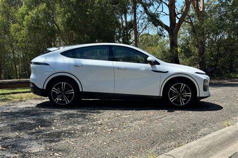 October 29, 2026 White crossover SUV parked on a gravel lot with trees in the background.