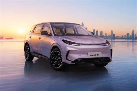 October 29, 2026 White futuristic SUV photographed from the front-left, parked on a reflective icy surface with a sunset and city skyline in the background.